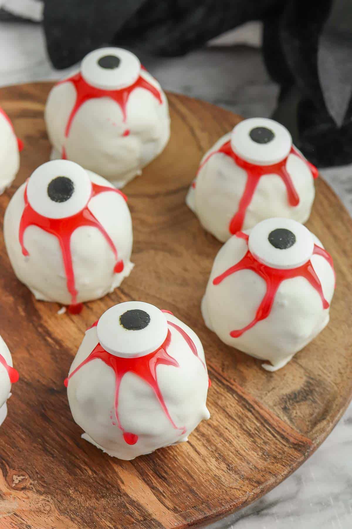 A plate of white and red oreo eyeballs on a wood board.