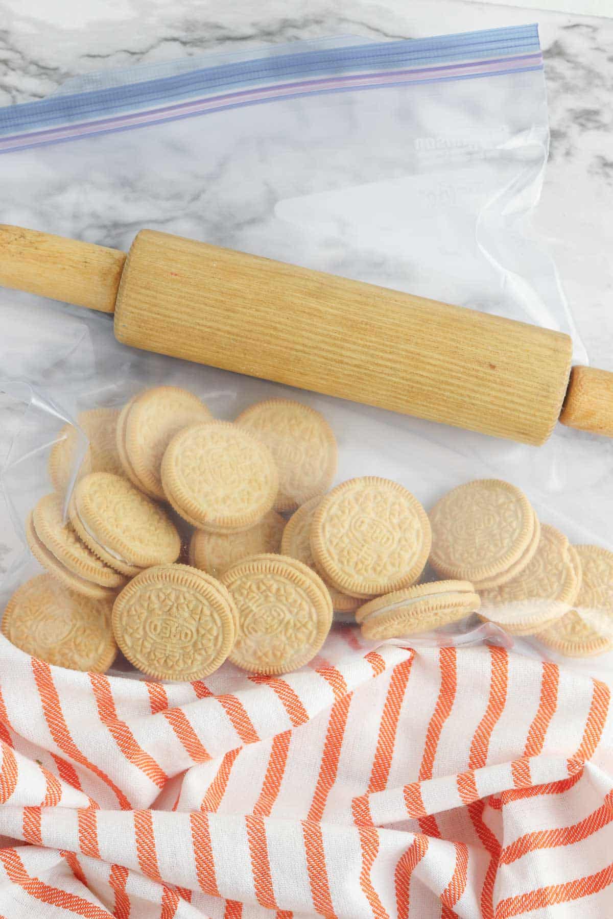 golden oreo cookies in a plastic bag with a rolling pin.