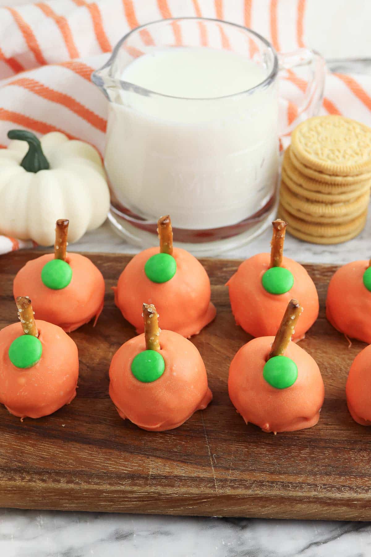 eight no-bake Pumpkin oreo balls on a wooden cutting board.