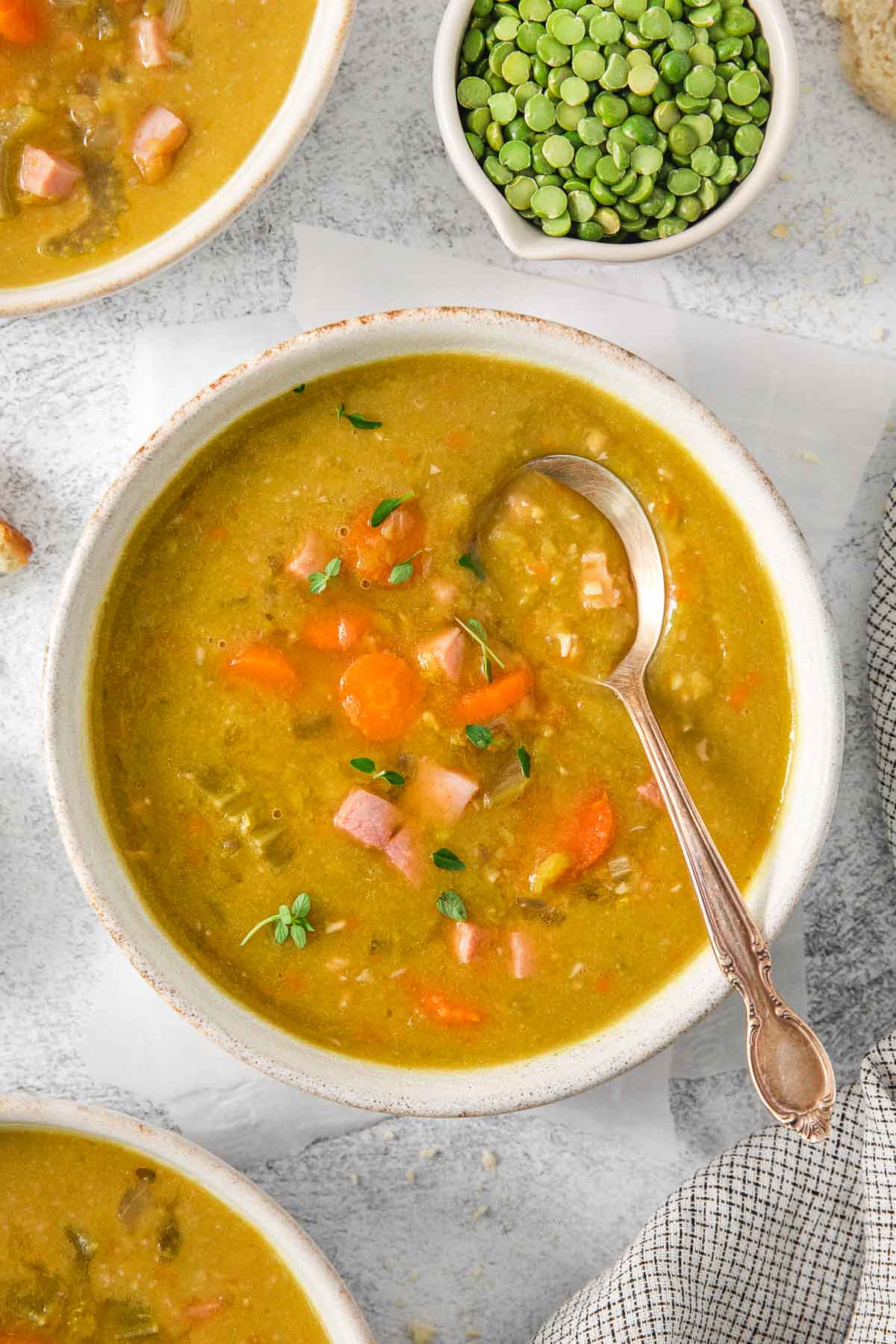 A bowl of classic split pea soup with ham with a spoon in it.