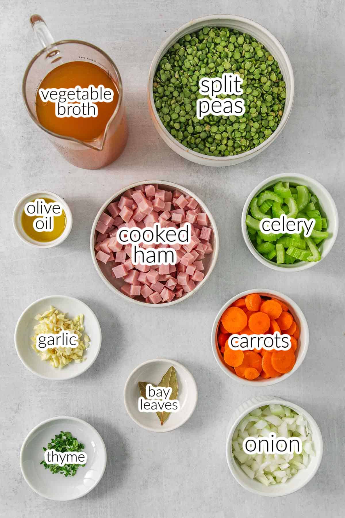 Ingredients for split pea soup - split peas, vegetable broth, celery, ham chunks, carrots, bay leaves, onions, olive oil, thyme leaves and garlic.