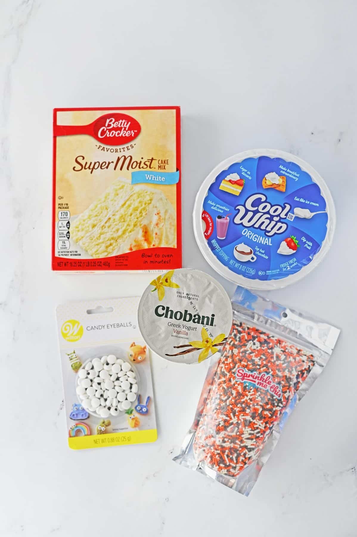 ingredients for an easy funfetti dip recipe - box cake mix, container of cool whip, small carton of vanilla yogurt, candy eyes, and a big of sprinkles.