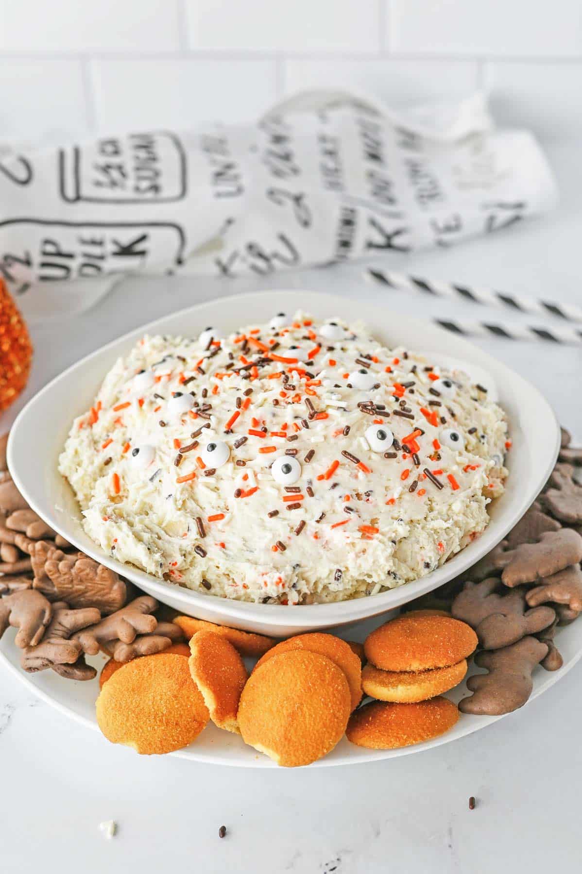 A bowl of halloween dessert dip with choclate animal crackers and vanilla wafers.