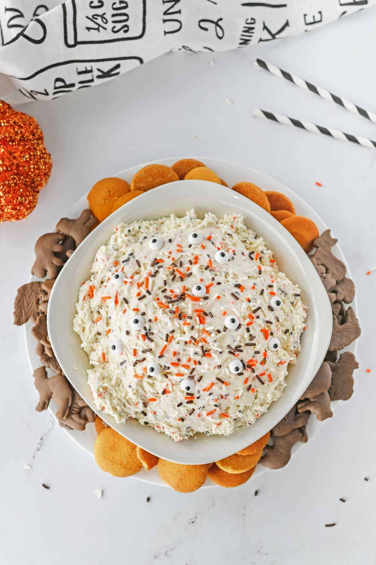 A bowl of dunkaroo dip with sprinkles on top and chocolate crackers and vanilla wafers.