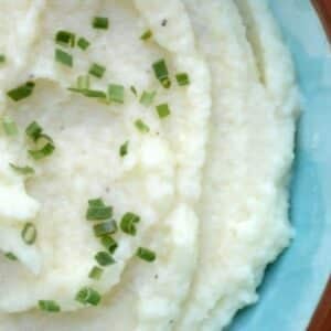 A bowl of mashed cauliflower with chives on top.