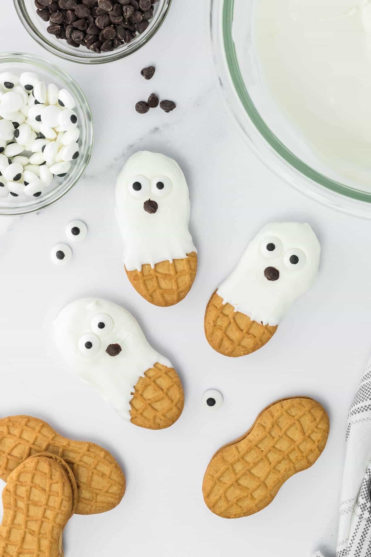 Ghost nutter butter cookies with white frosting, candy eyes and chocolate chip mouths.