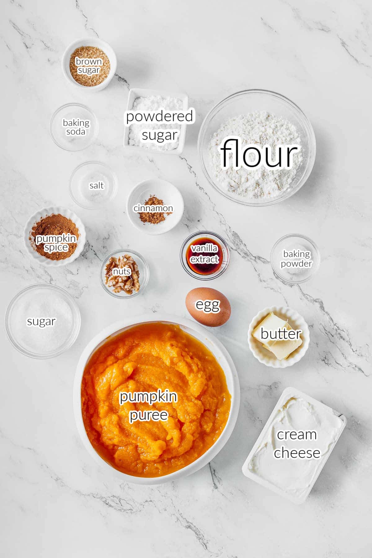 several bowls with pumpkin bread ingredients: pumpkin puree, flour, egg, butter, sugar, vanilla, cream cheese, powdered sugar and spices.