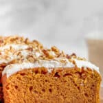 A slice of pumpkin bread with cream cheese frosting on a plate.