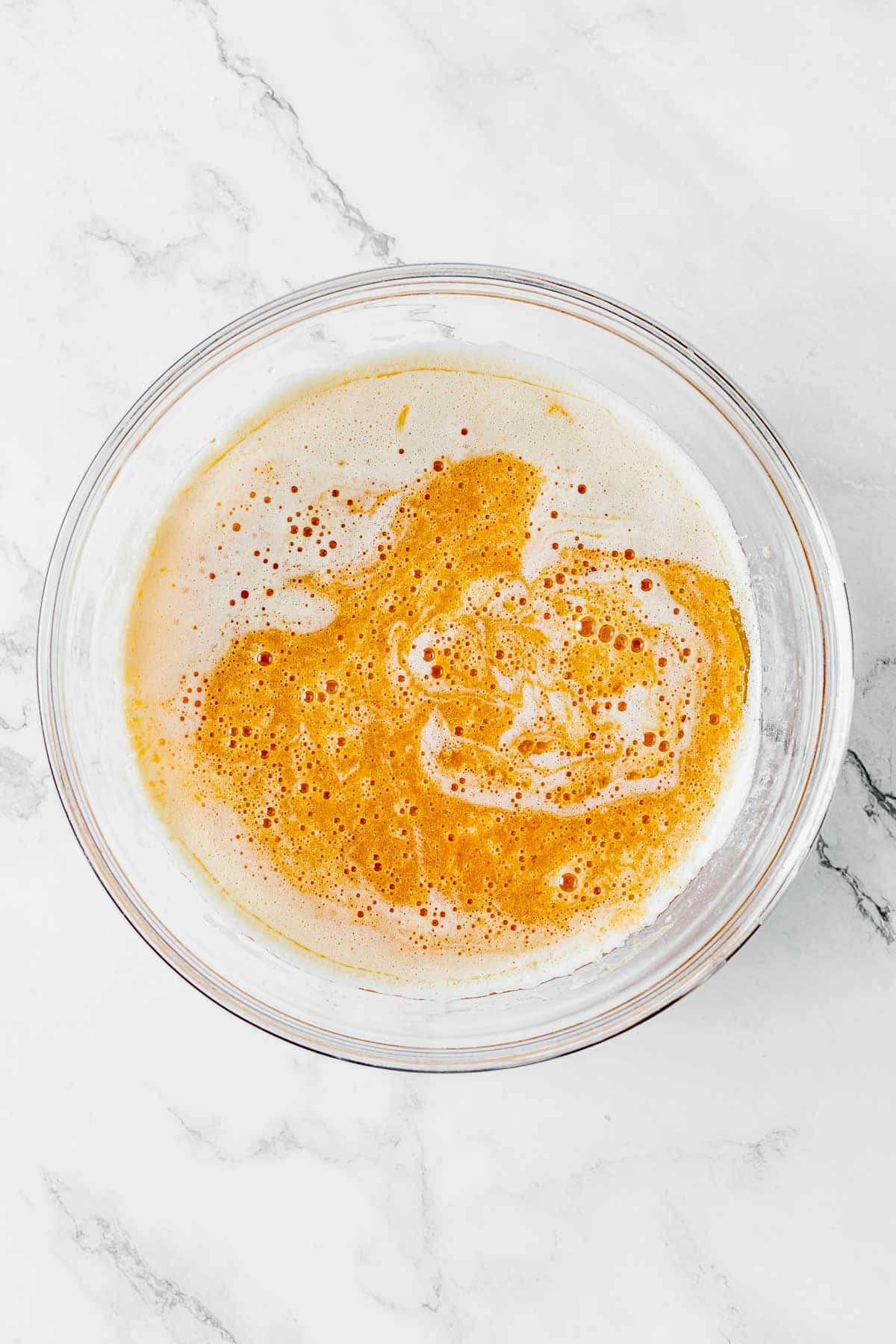 A glass bowl with pumpkin puree and milk in it.