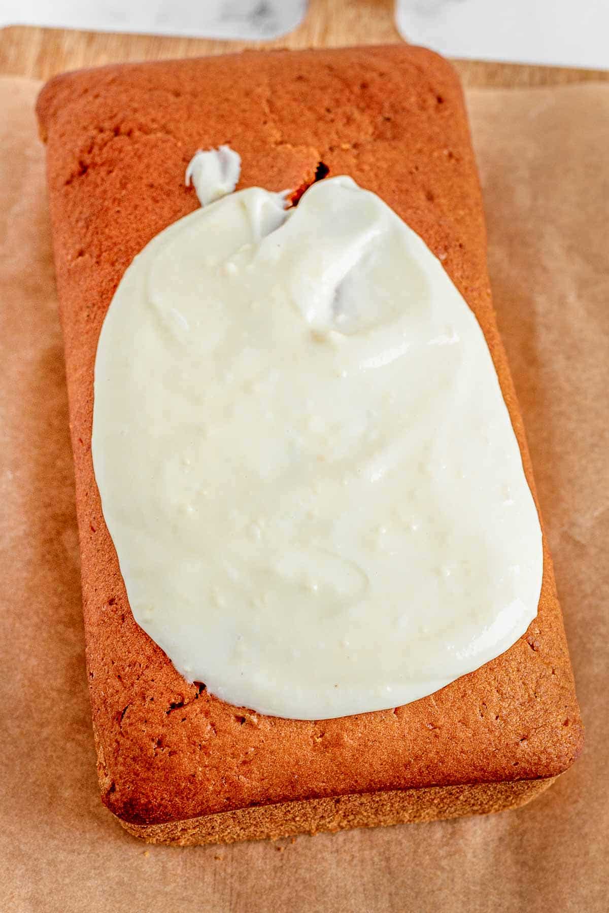 pumpkin bread loaf with frosting being spread on top of it.