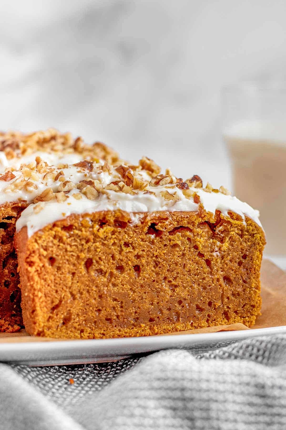 A slice of pumpkin bread with icing on a plate.
