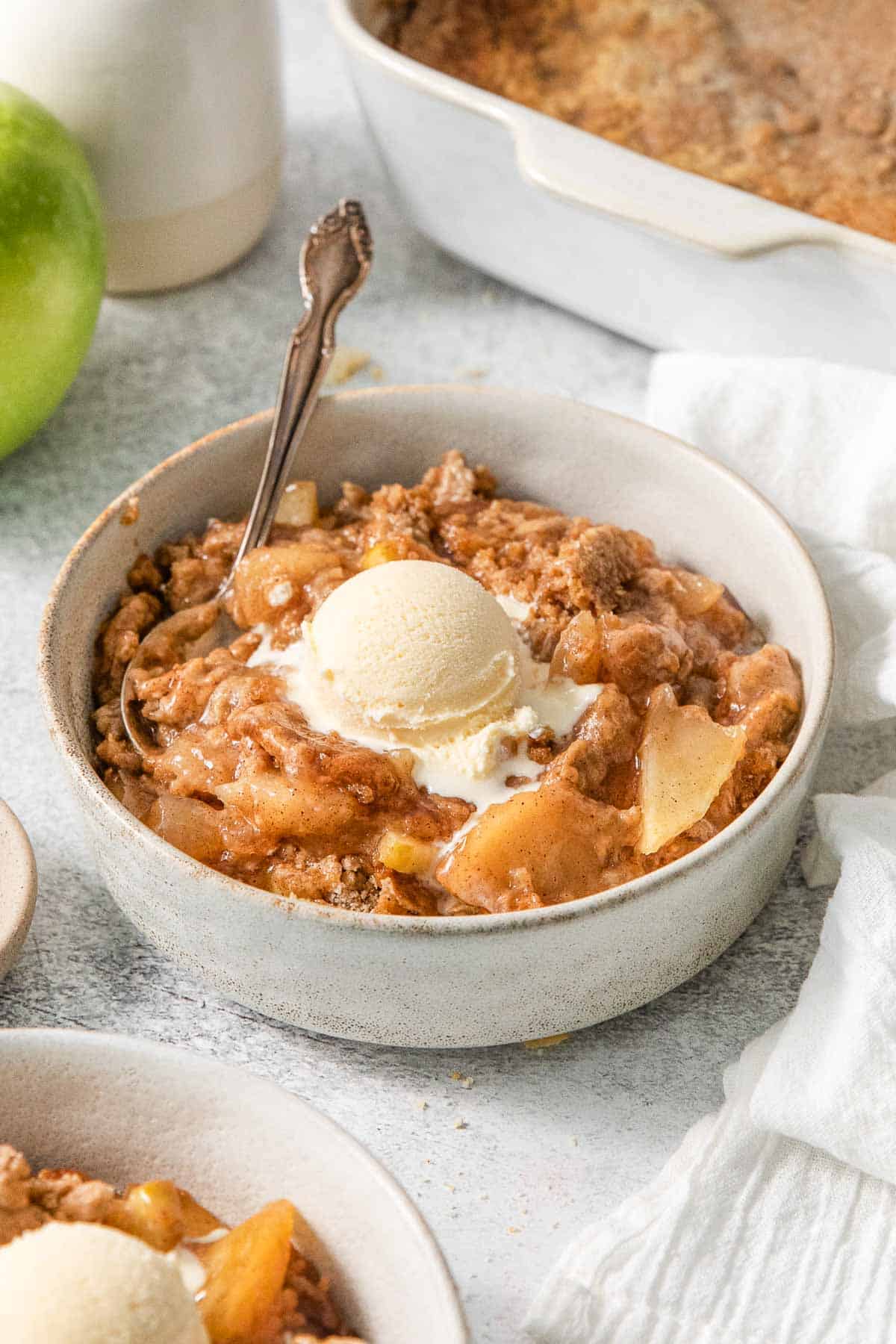 Apple dump cake in a bowl with a scoop of vanilla ice cream on top.