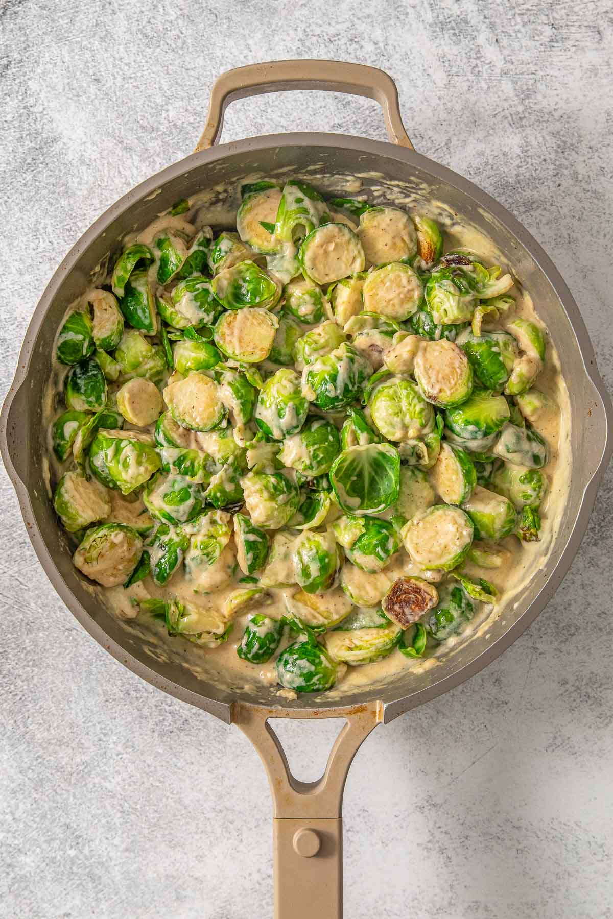 A skillet filled with brussel sprouts and sauce.