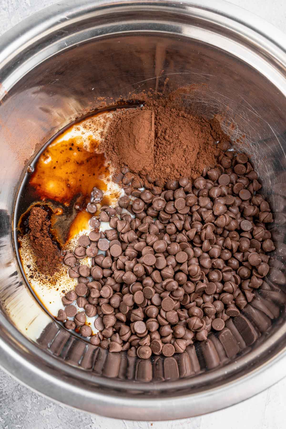 chocolate chips, condensed milk and cocoa powder in a silver bowl.
