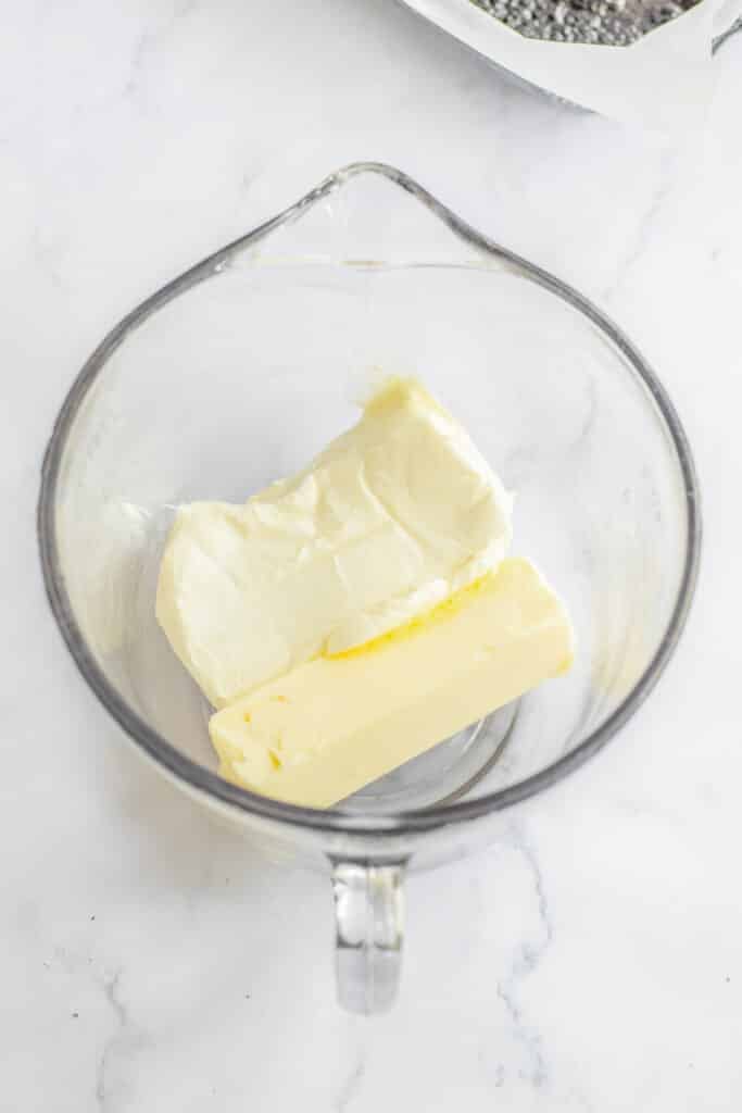 A bowl of butter and block of cream cheese in a glass mixing bowl.