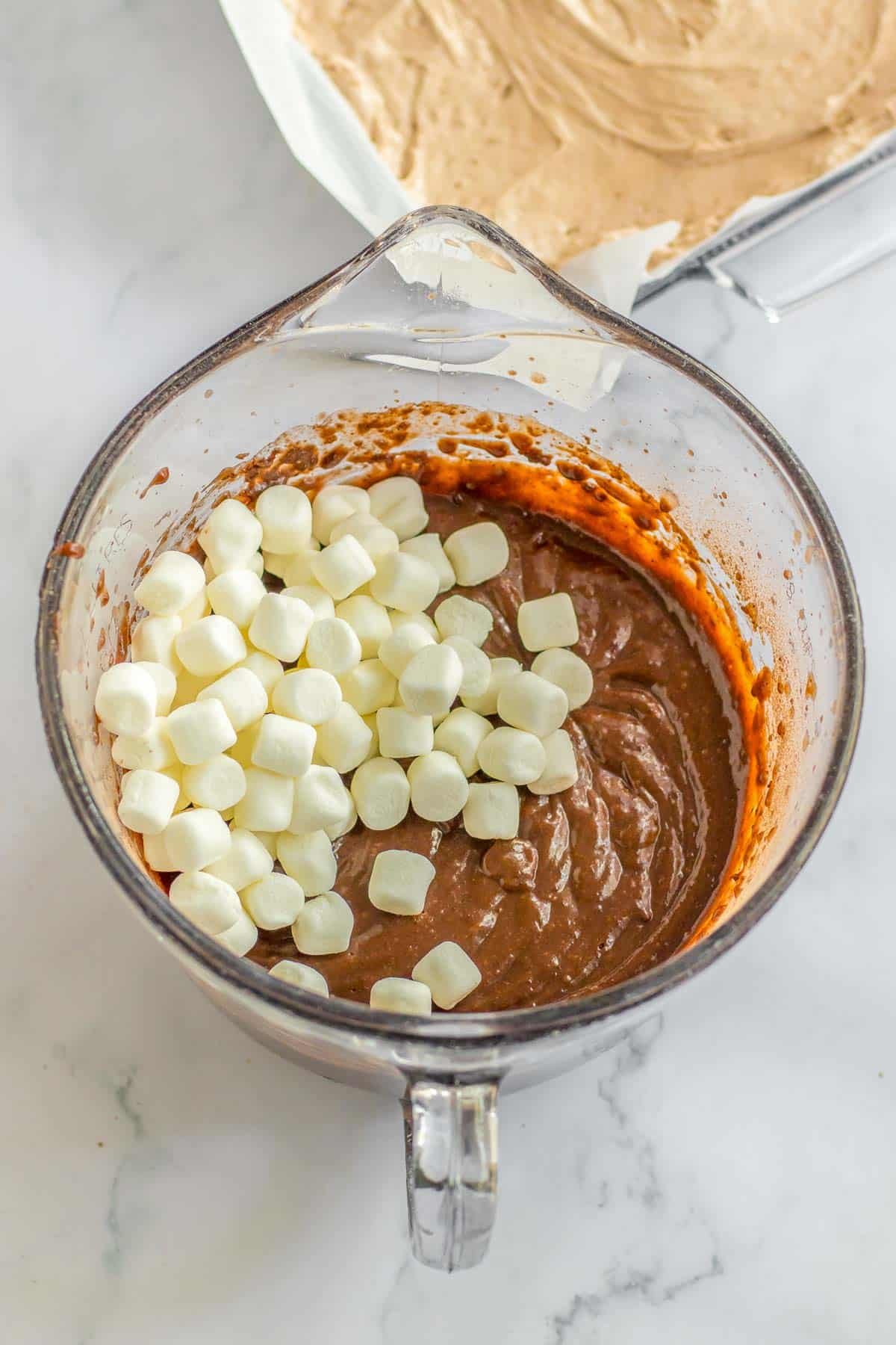 glass mixing bowl with chocolate pudding topped with mini marshmallows.