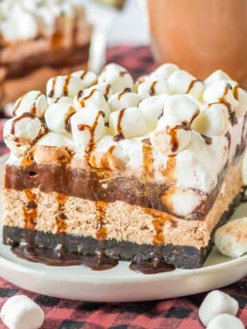 A slice of layered chocolate oreo delight recipe topped with mini marshmallows on a white plate.