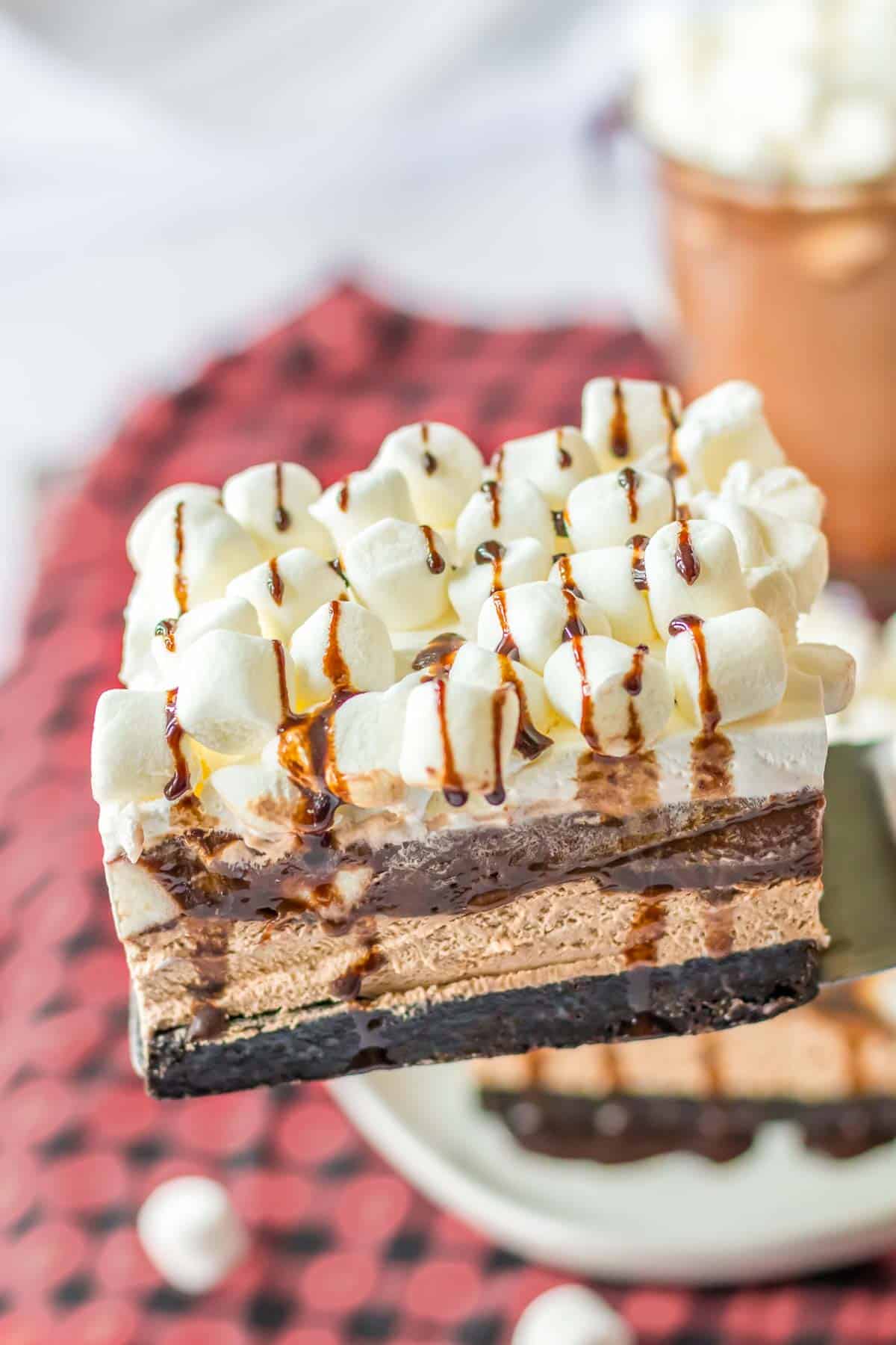 A piece of chocolate oreo delight recipe with marshmallows and chocolate drizzel on top.