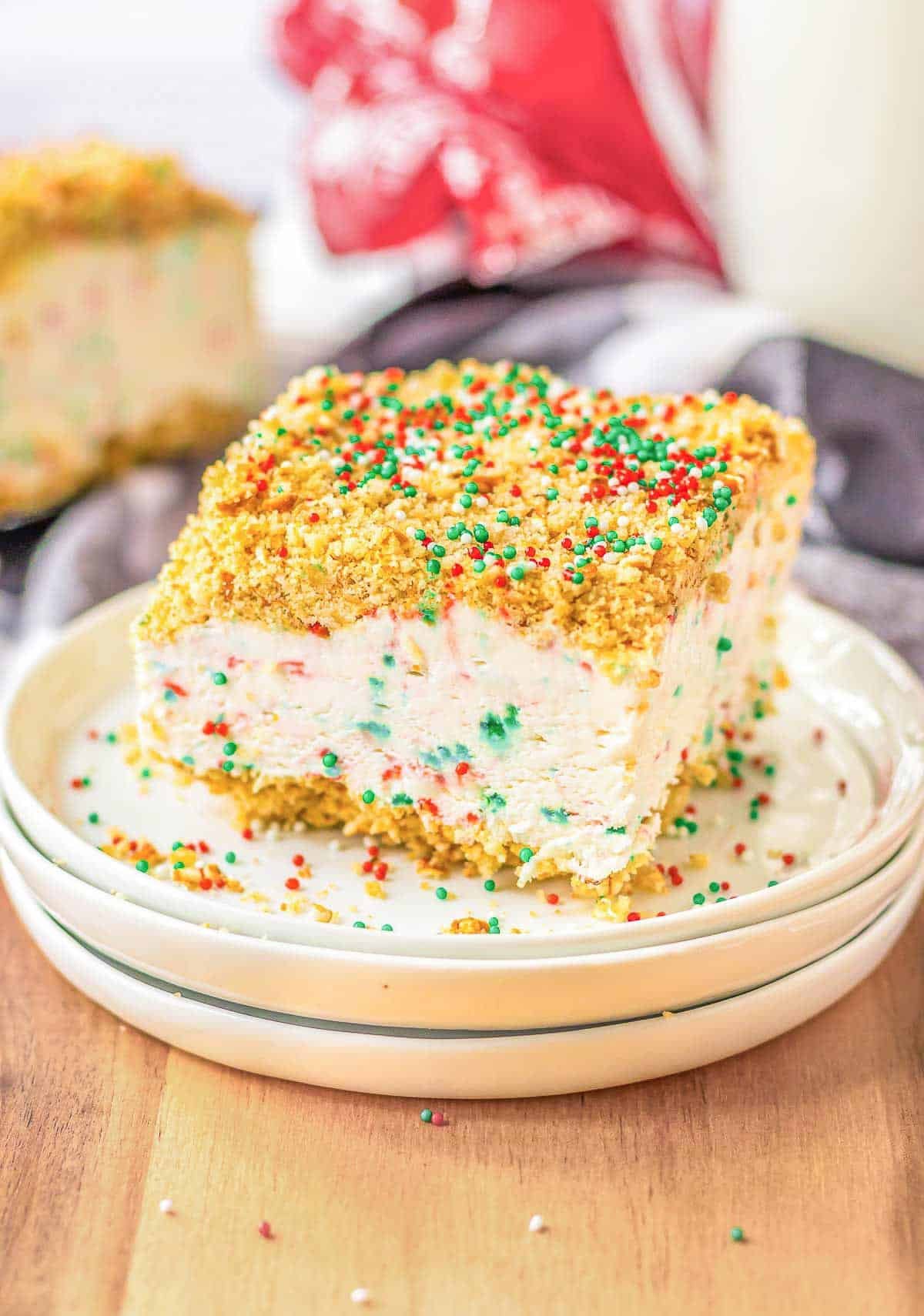 A slice of Christmas Crunch Cake with sprinkles on a white plate.