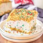 A slice of Christmas Crunch Cake with sprinkles on a white plate.