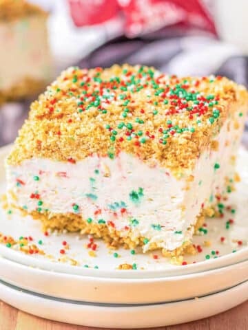 A slice of Christmas Crunch Cake with sprinkles on a white plate.