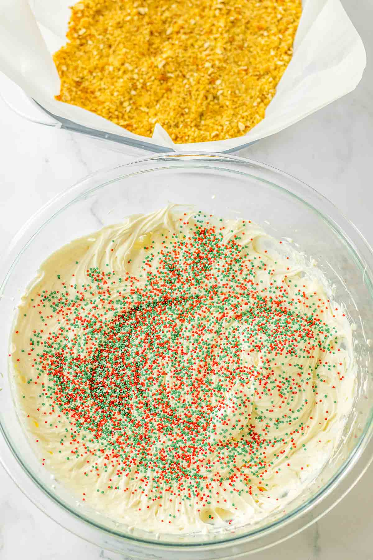 Cream cheese mixture topped with christmas sprinkles in glass bowl.