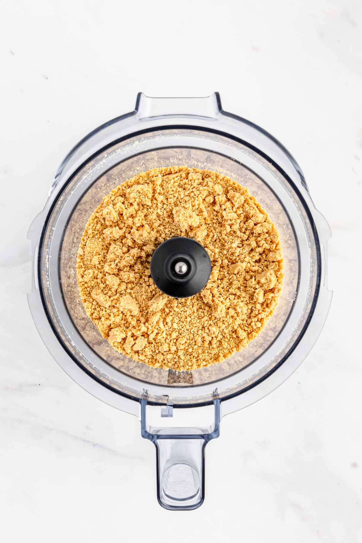 A food processor filled with a golden oreo crumbs.