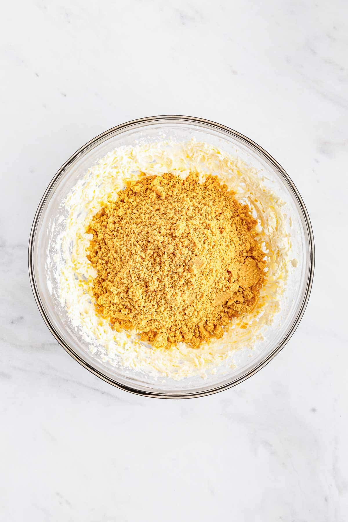 A glass bowl with whipped cream cheese with crushed golden oreos on top.