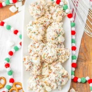 A pile of several pieces of crockpot candy with sprinkles on a white plate.