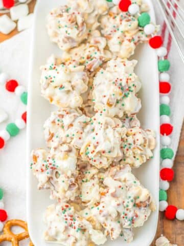 A pile of several pieces of crockpot candy with sprinkles on a white plate.