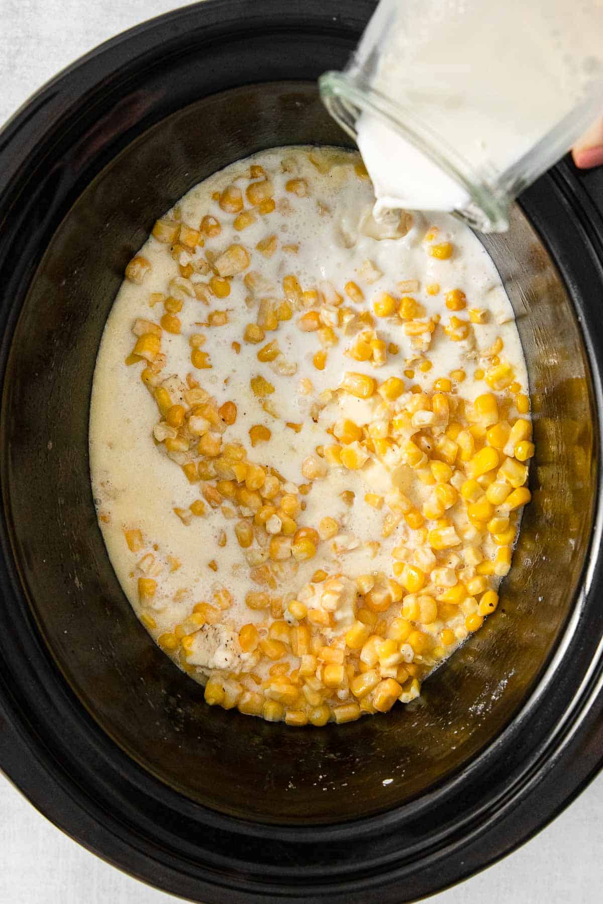 Corn, heavy cream, cubed butter, granulated sugar, salt and pepper added to crockpot for cooking.