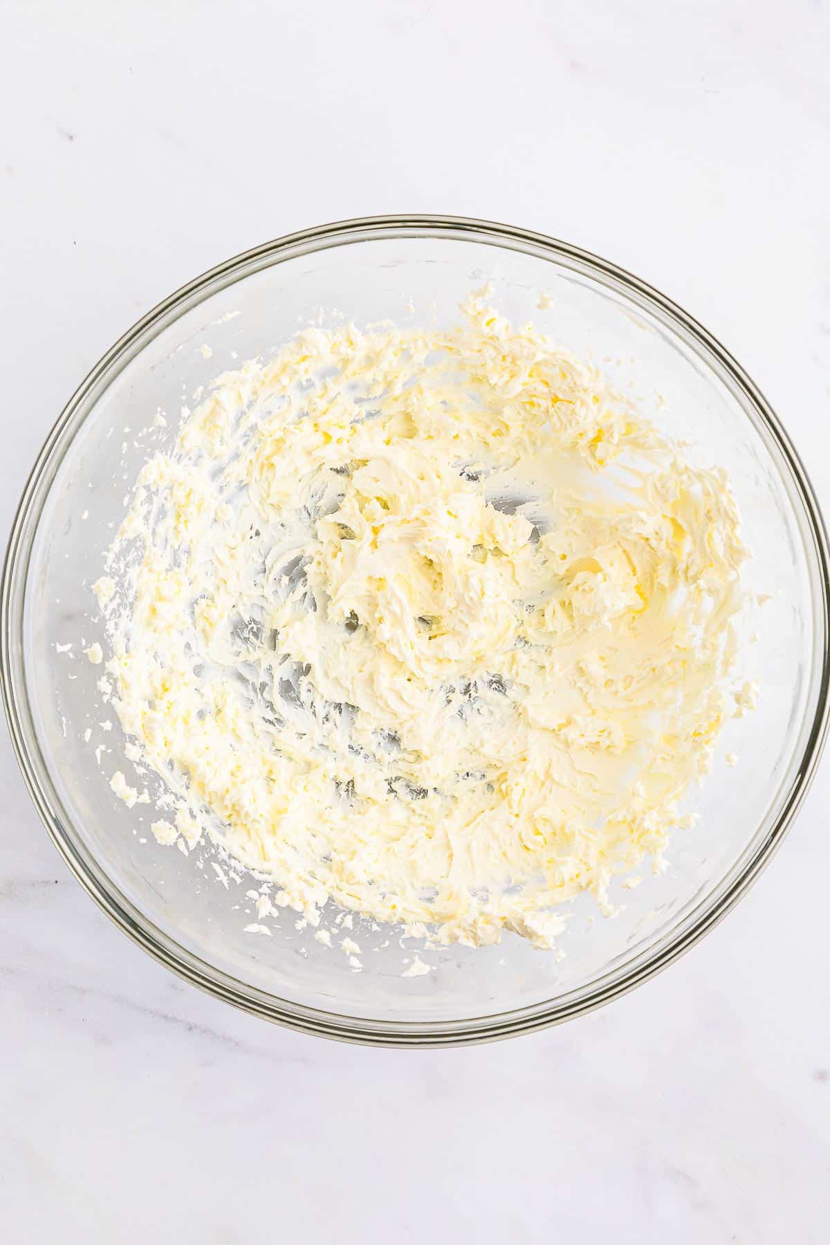 Cream cheese beaten in a glass mixing bowl.