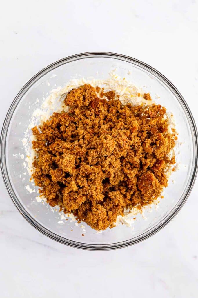 Cream cheese and crumbled gingerbread cake in a large glass bowl.
