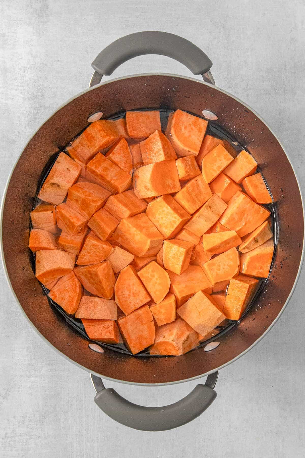 Cube sliced sweet potatoes in a large pot.
