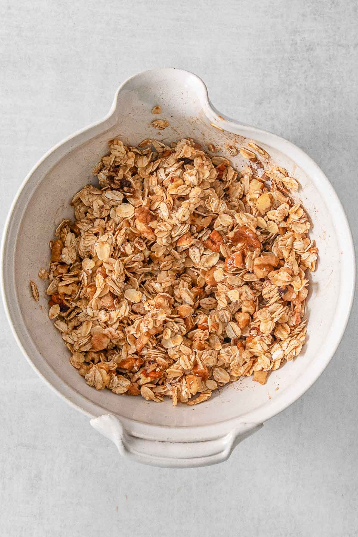 Oats, pecans, cinnamon, salt and butter mixed together in a large white bowl.