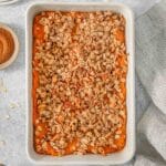 Healthy sweet potato casserole with pecan oat topping in a white baking dish.