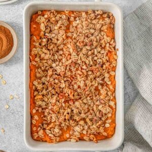 Healthy sweet potato casserole with pecan oat topping in a white baking dish.