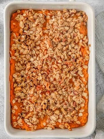 Healthy sweet potato casserole with pecan oat topping in a white baking dish.