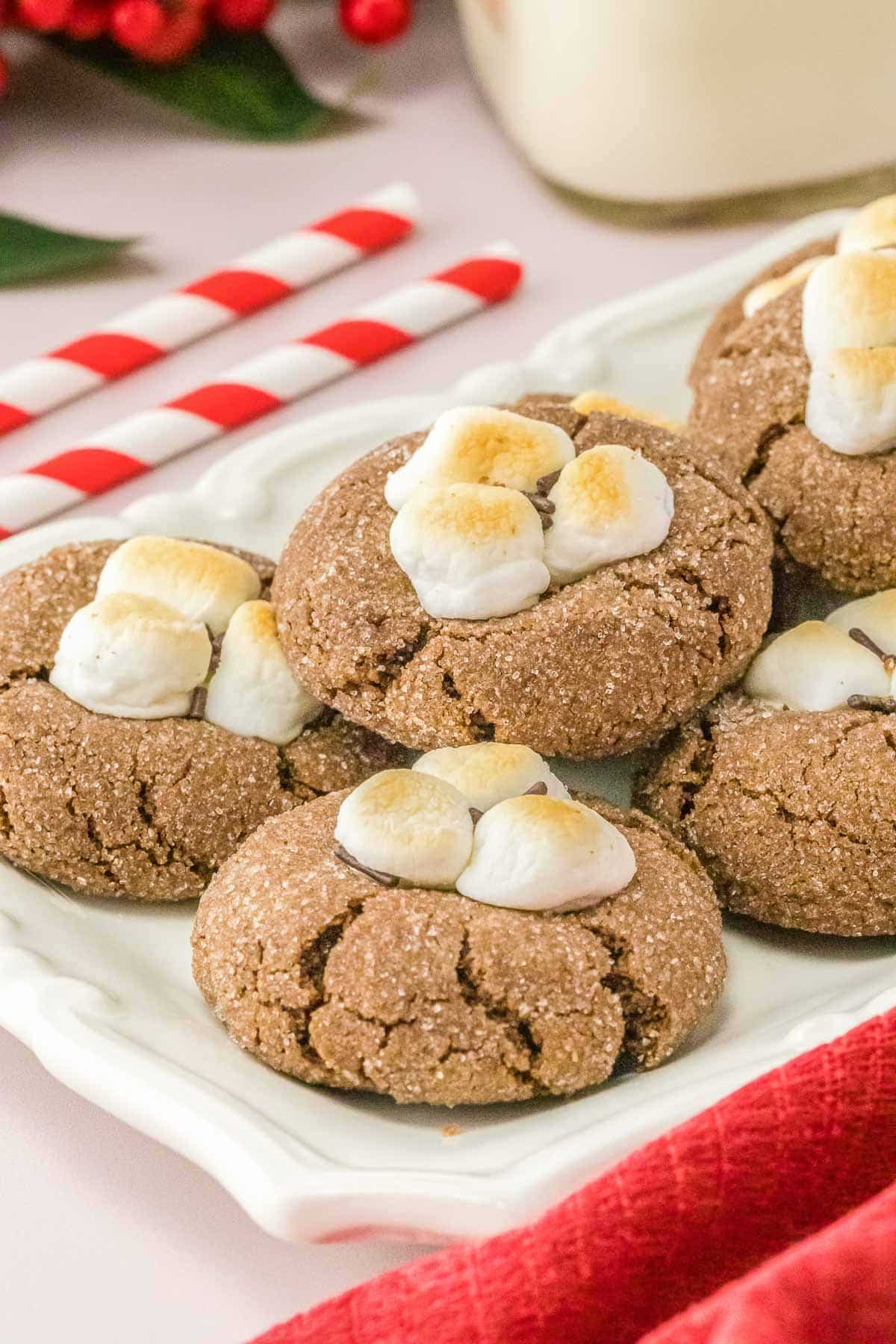 Multiple hot chocolate cookies with marshmallows on a plate.