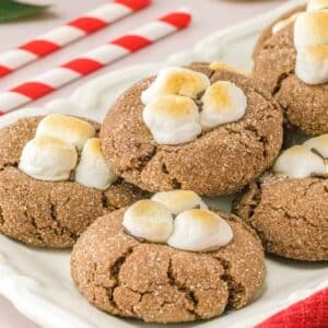 Multiple hot chocolate cookies with marshmallows on a plate.