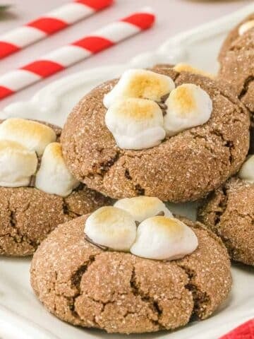 Multiple hot chocolate cookies with marshmallows on a plate.