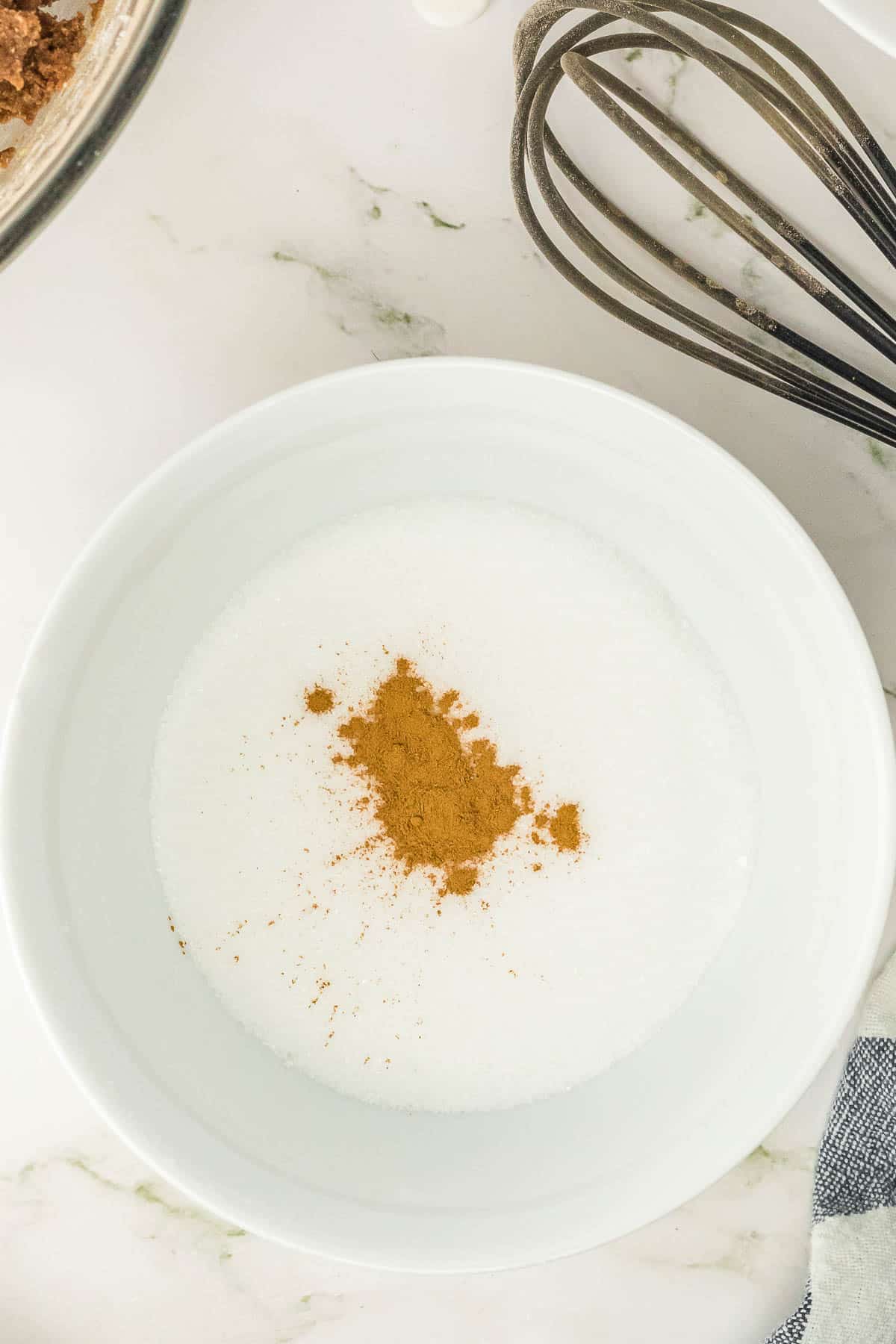 A white bowl with granulated sugar and cinnamon.