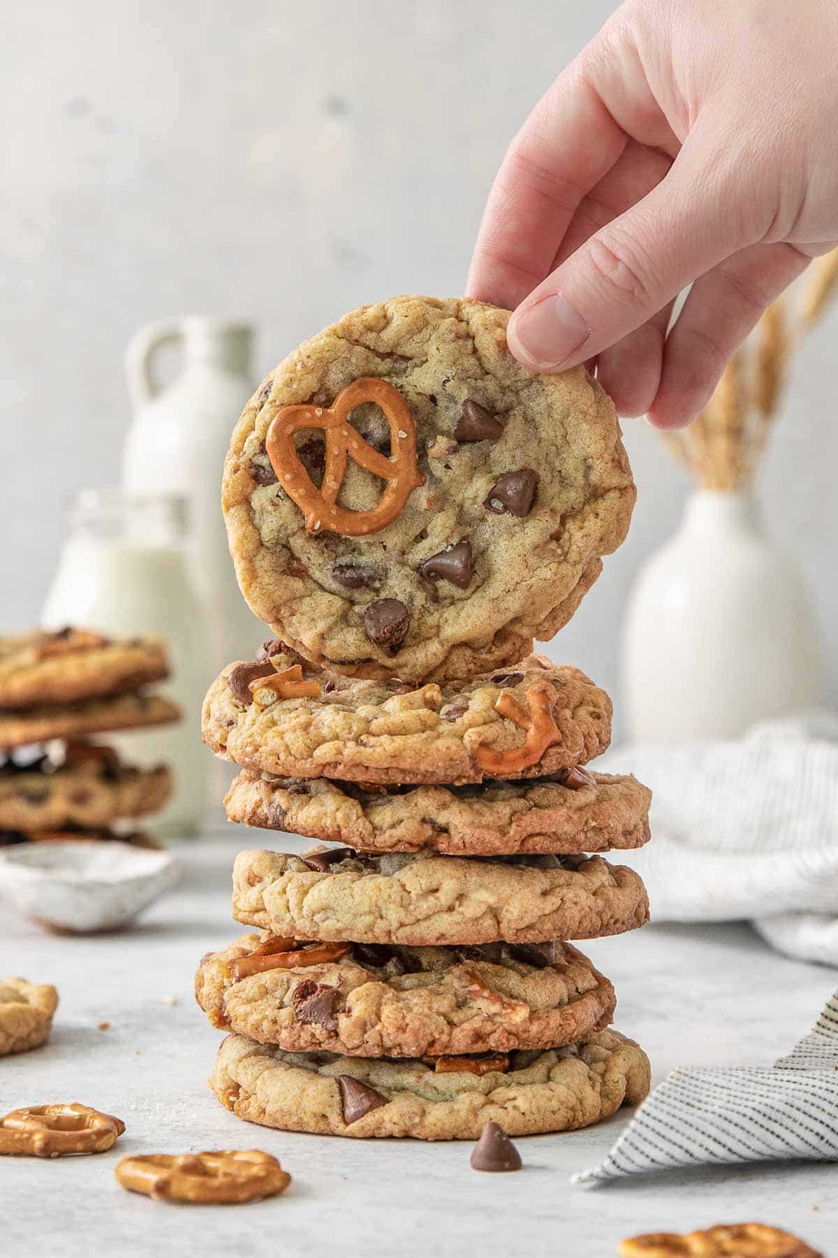 A hand is grabbing a cookie from a stack of Kitchen Sink Cookies.