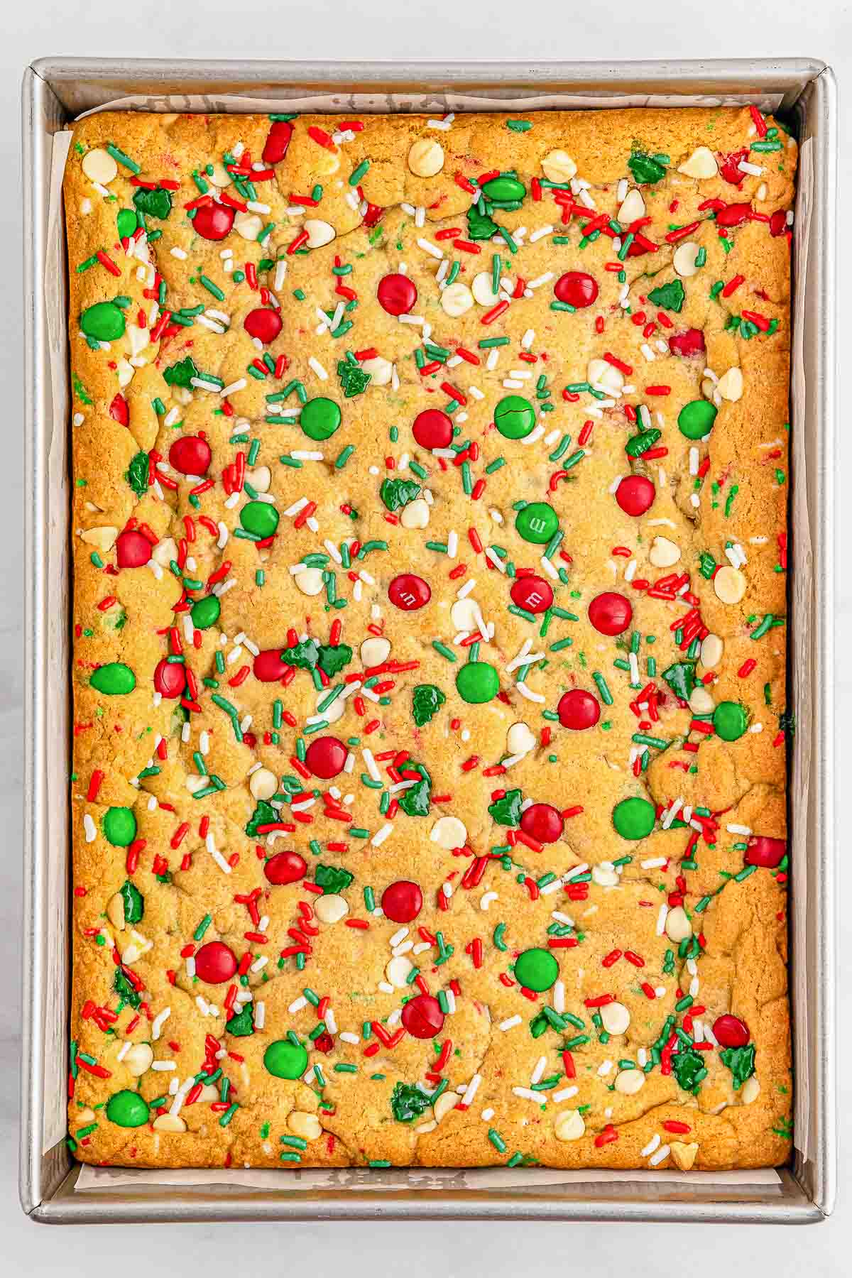M&M cookie sheet on a baking tray with red and green sprinkles.