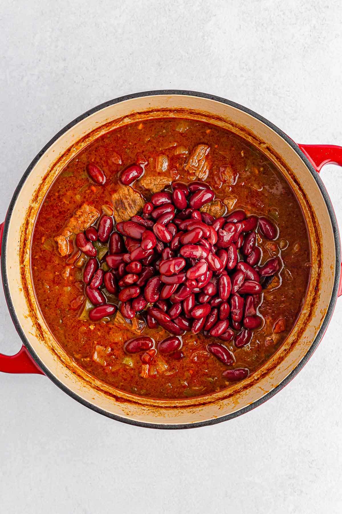 Chili beans in a red pot on a white background.
