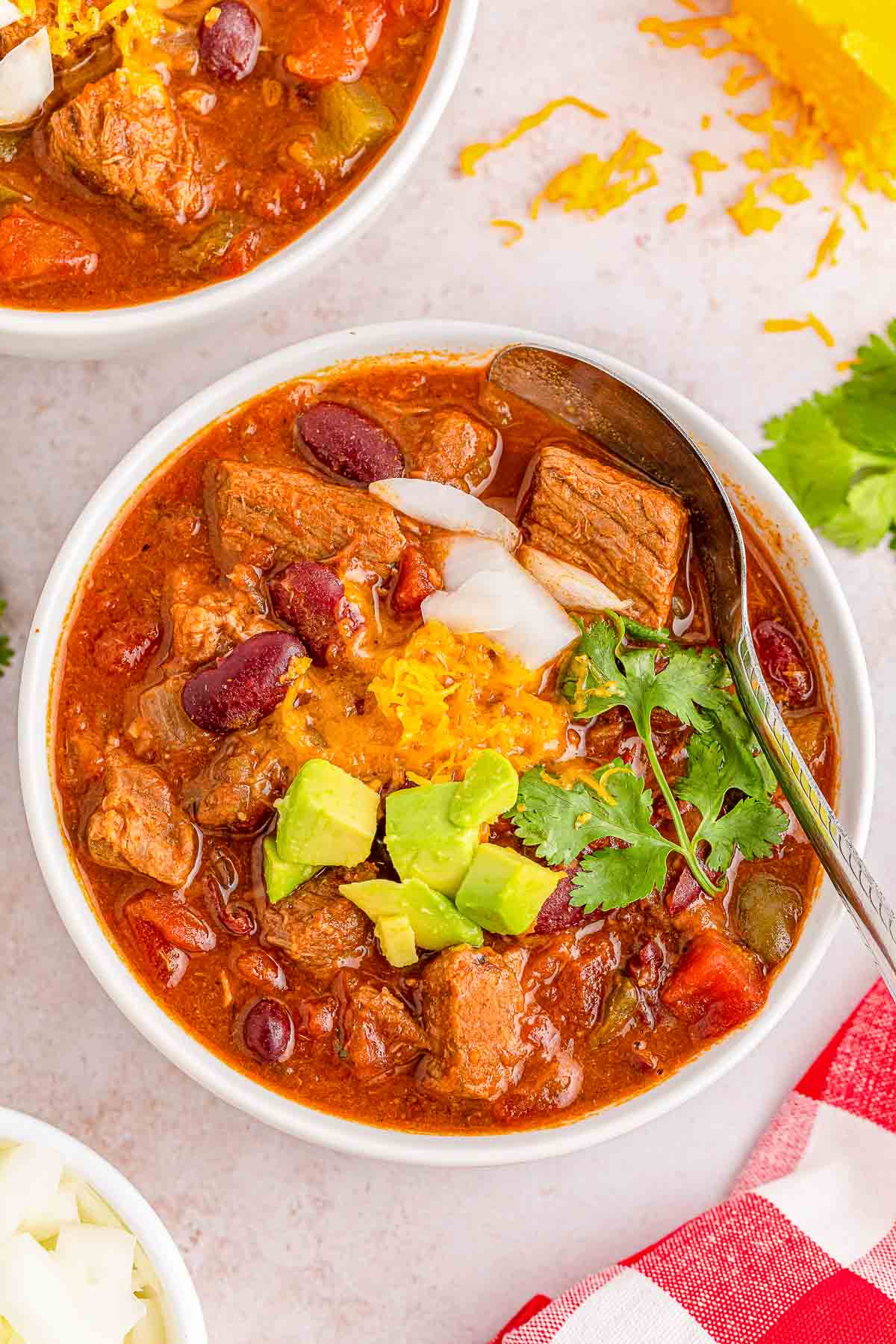 Two bowls of chili with beef and guacamole.