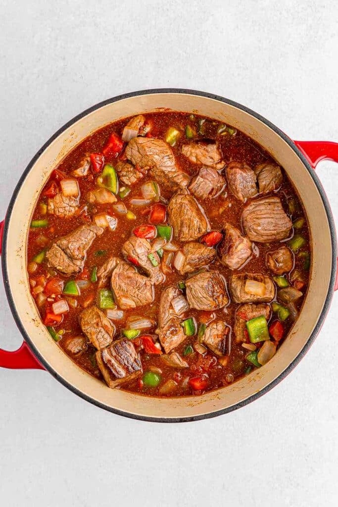 Beef stew in a red pot on a white background.