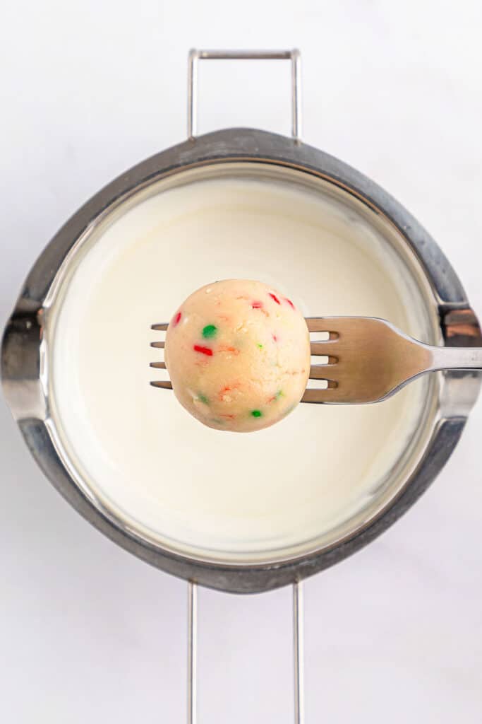 A fork is being used to eat a cake with sprinkles on it.