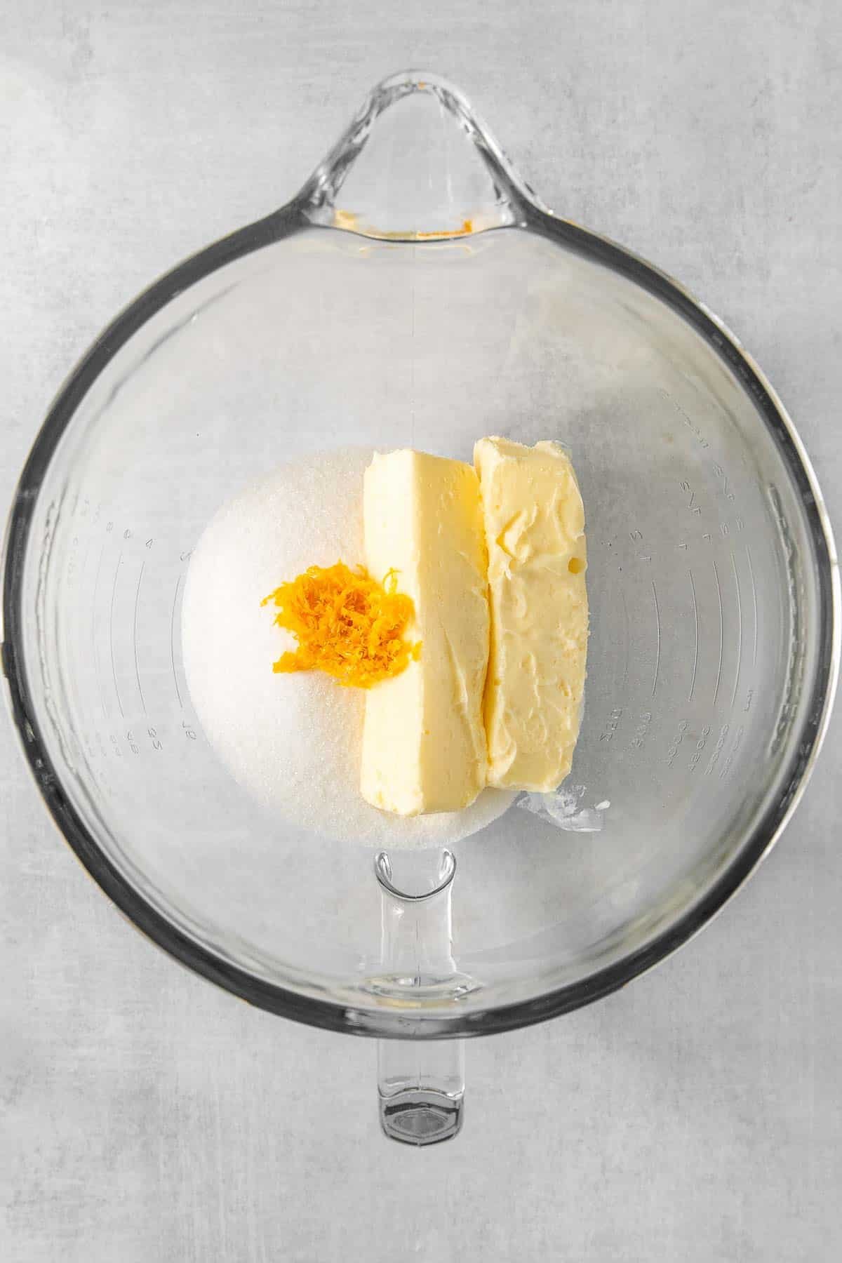 Butter, sugar and orange zest in a glass mixing bowl.