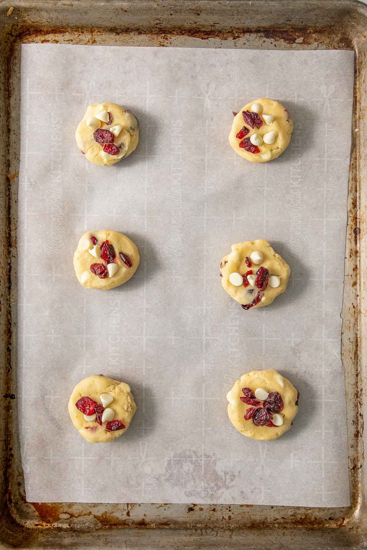 White chocolate cranberry cookie dough scooped onto a baking sheet.
